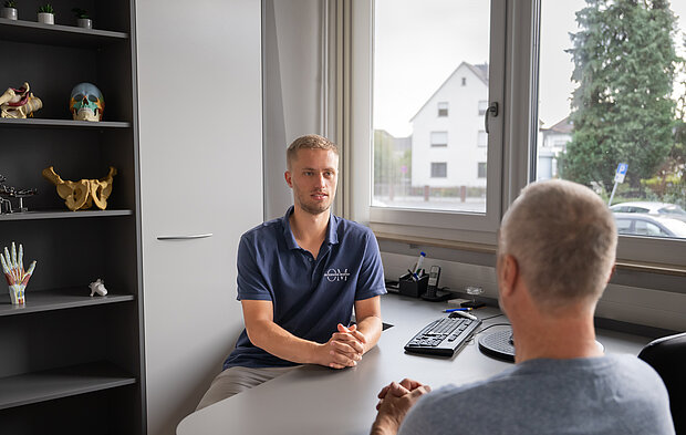 Osteopath in Maintal führt ein Anamnesegespräch mit einem Patienten in der Praxis