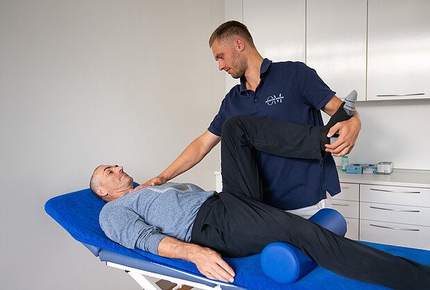 Osteopath behandelt den Herzbereich mit neurofunktioneller Technik während das Bein gestützt wird